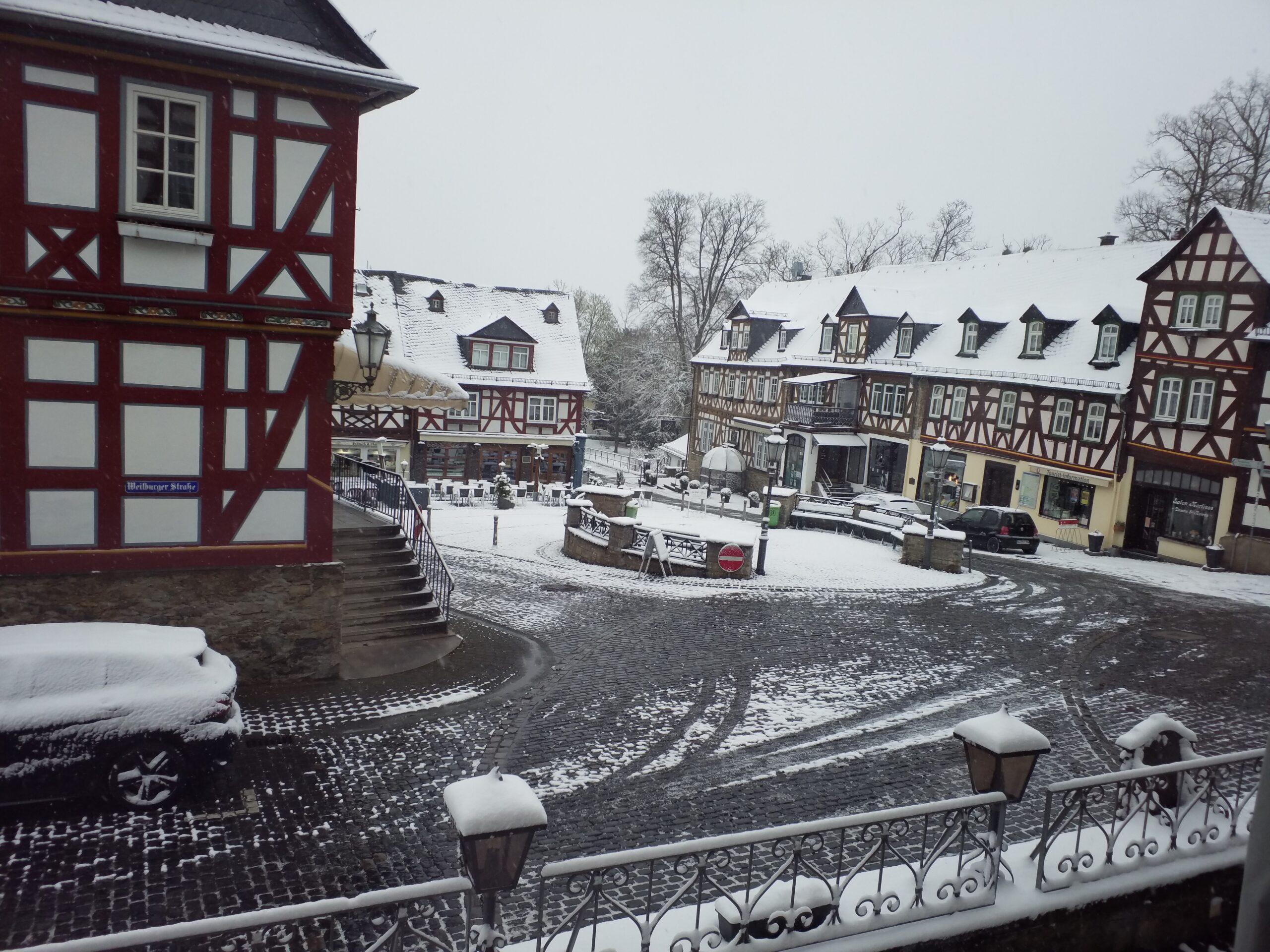 Ortsmitte mit Fachwerkhäusern und Dorfplatz, beschneit.