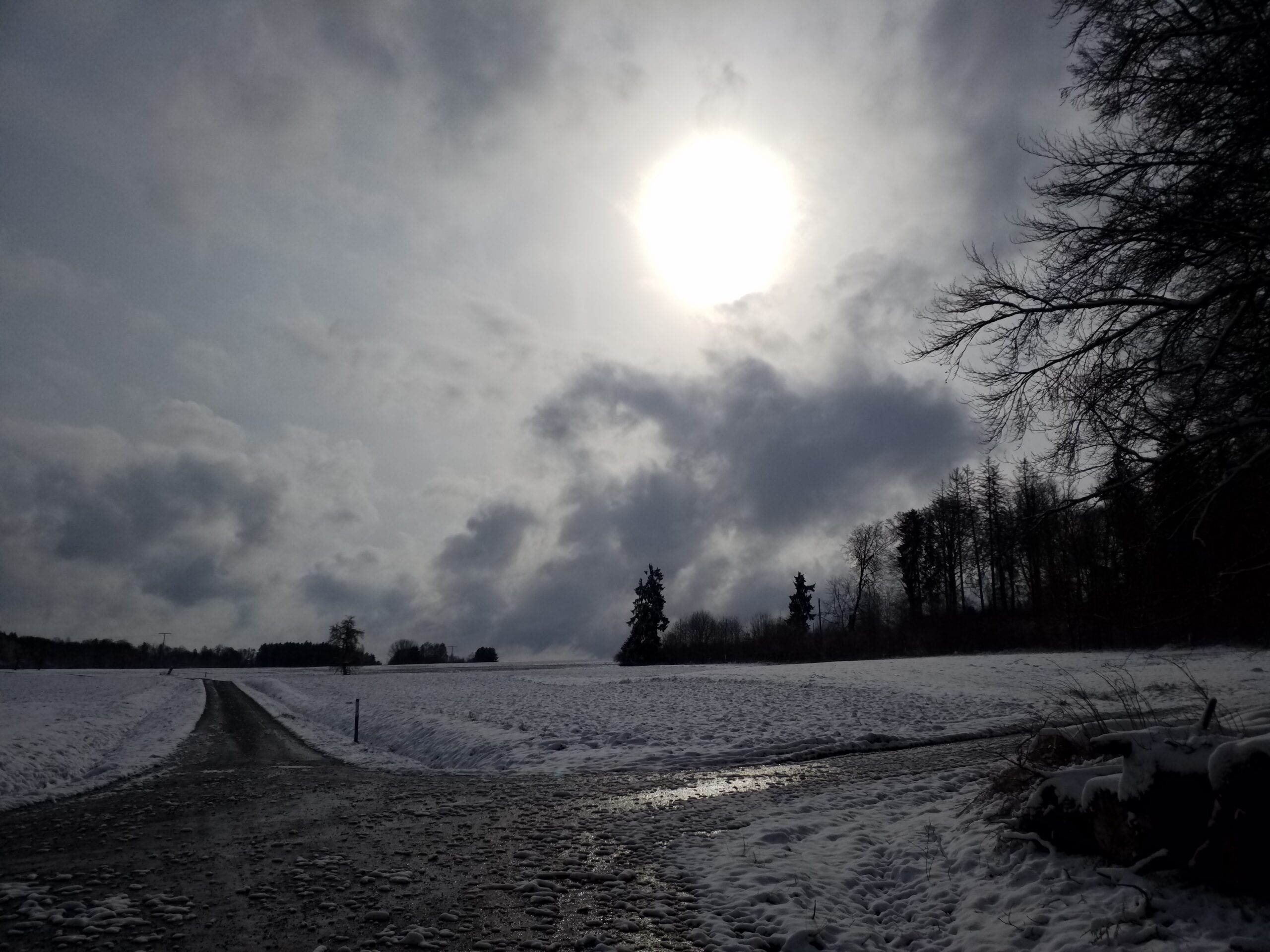 Winterwolkenhimmel über verschneiter Hochebene, Wegekreuzung.
